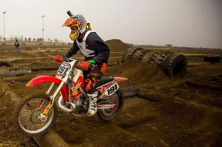 Jake riding a red Honda, number 191, over logs in an endurocross section